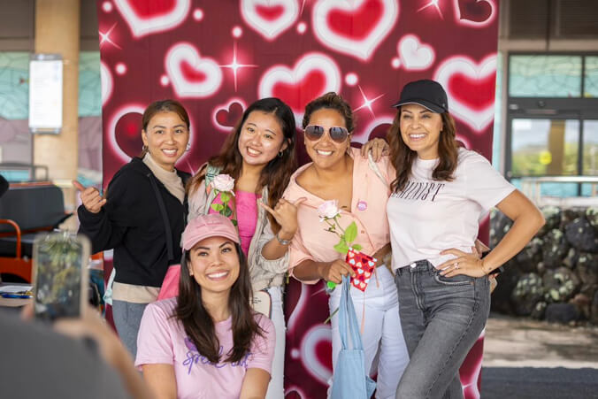 Students smiling in front of a valentine's day wall