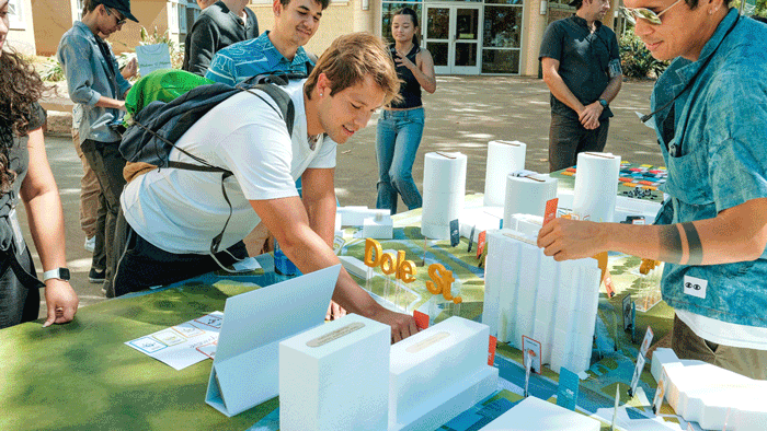 student placing card on 3 d map of u h manoa